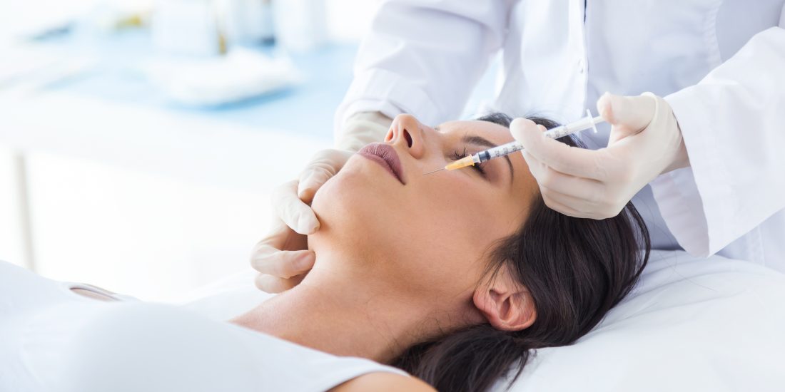 Portrait of beautiful young woman getting botox cosmetic injection in her face.