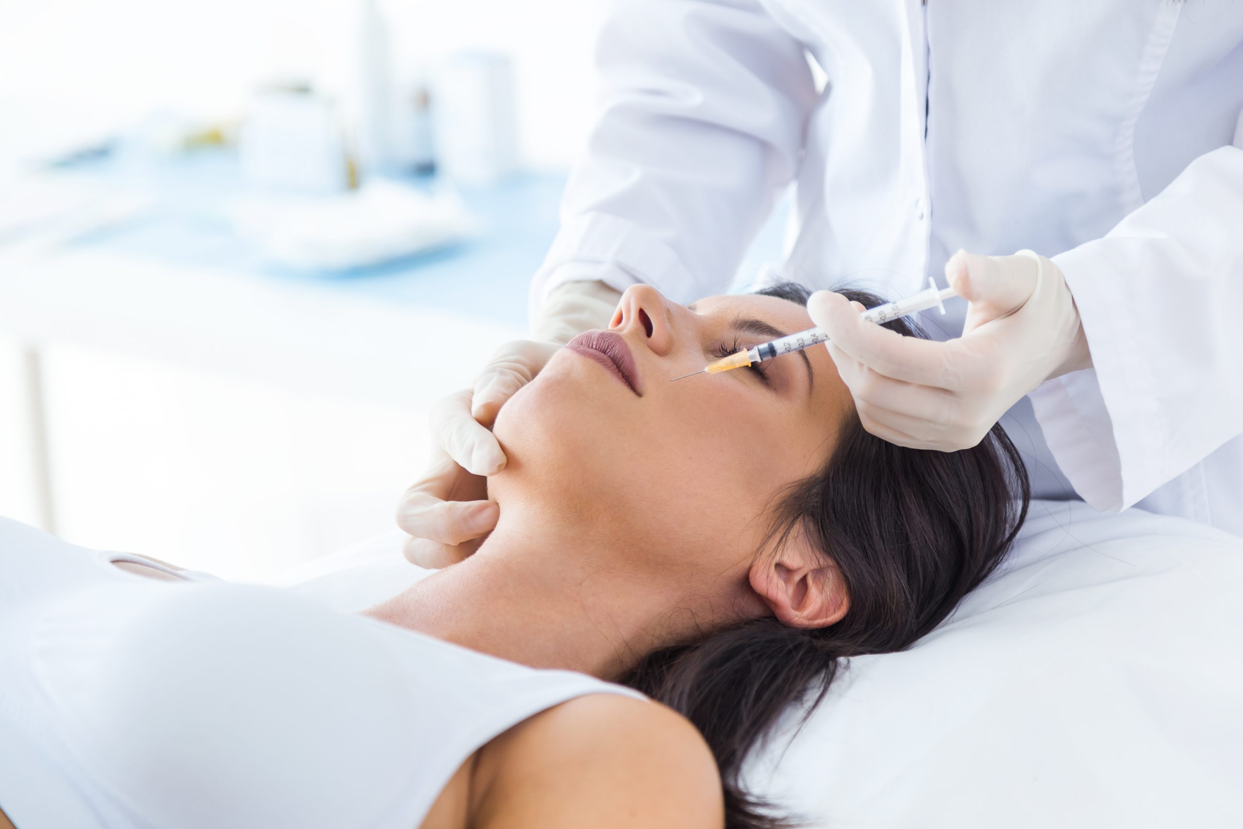 Portrait of beautiful young woman getting botox cosmetic injection in her face.